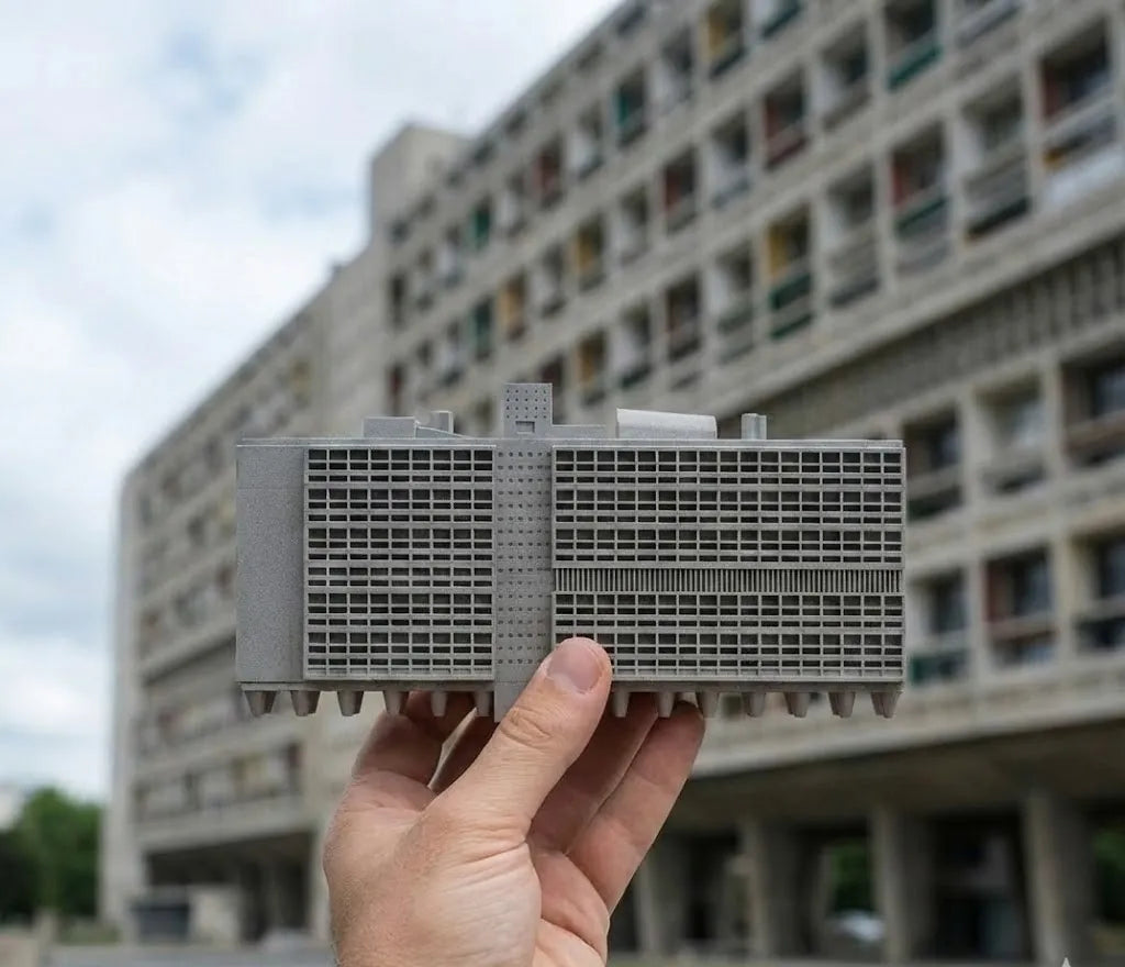 The concrete Marseille model held in front of the original Unité d’Habitation building.