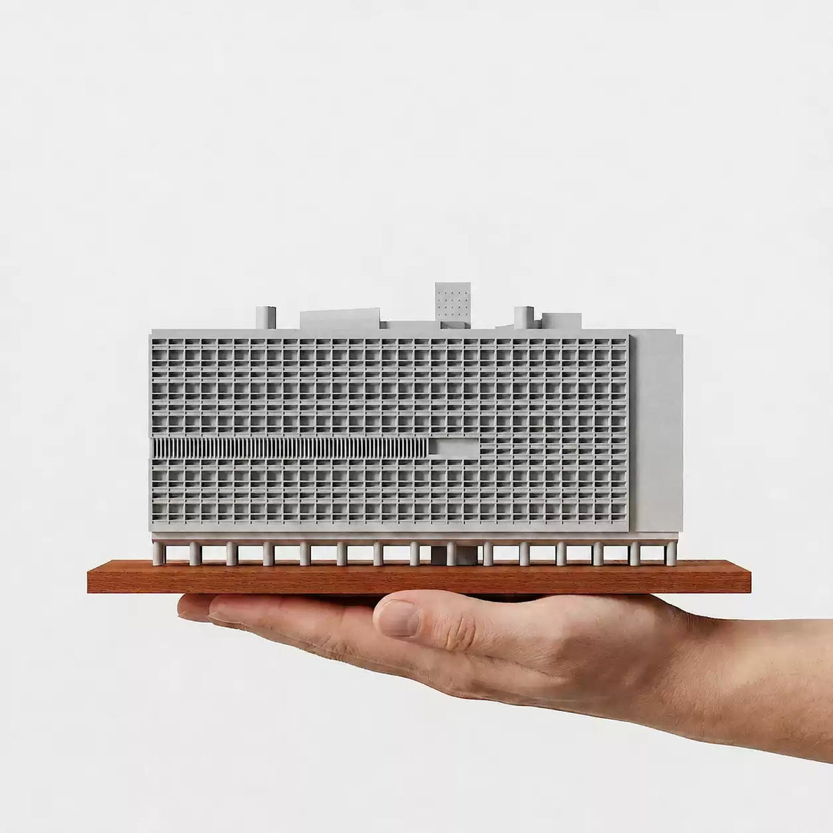 CONHEART Marseille Housing Unit concrete model supported on a hand, showing its front façade.