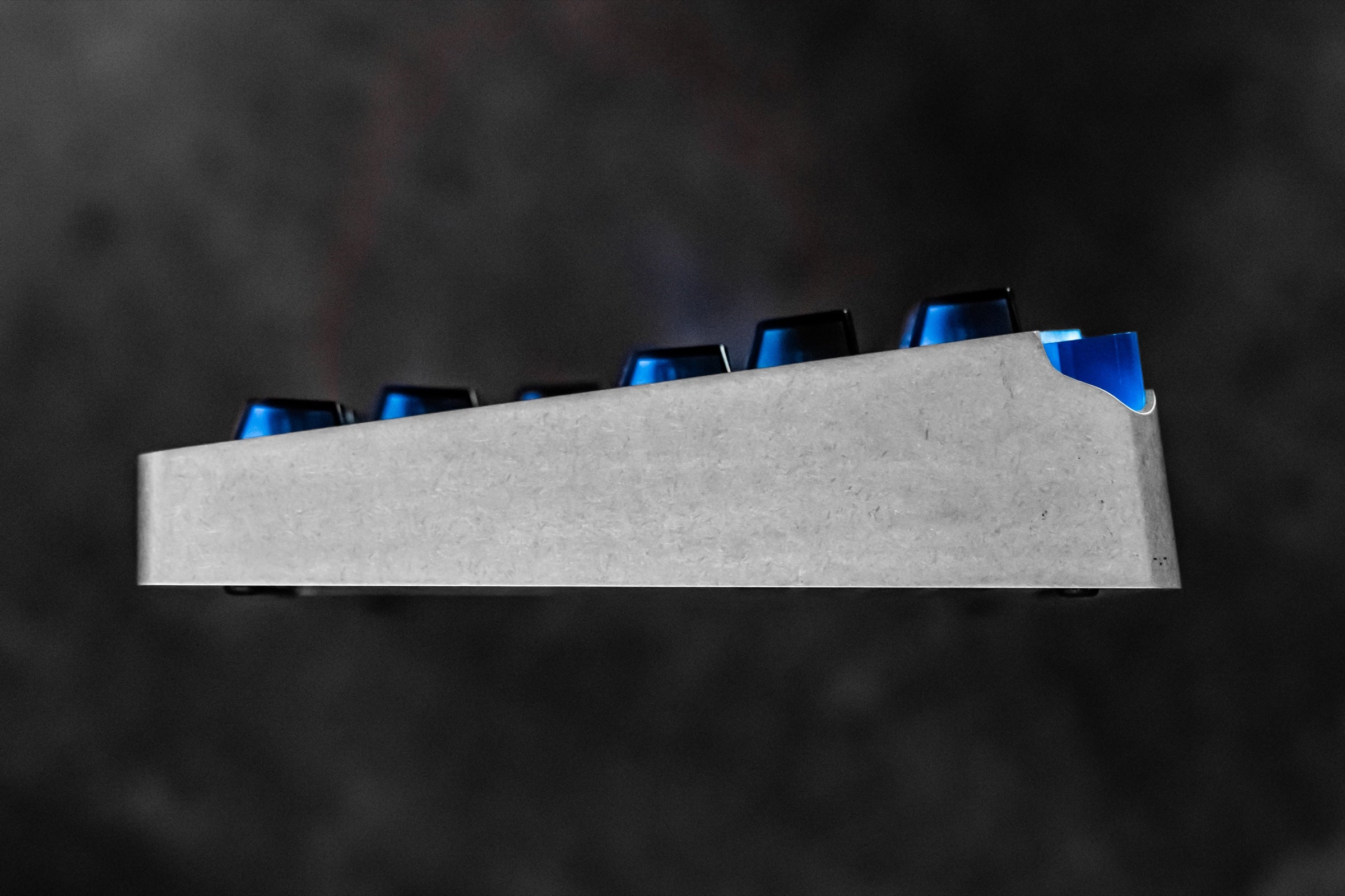 Low side profile of the aluminum keyboard case with the translucent corner module rising above the rear edge.