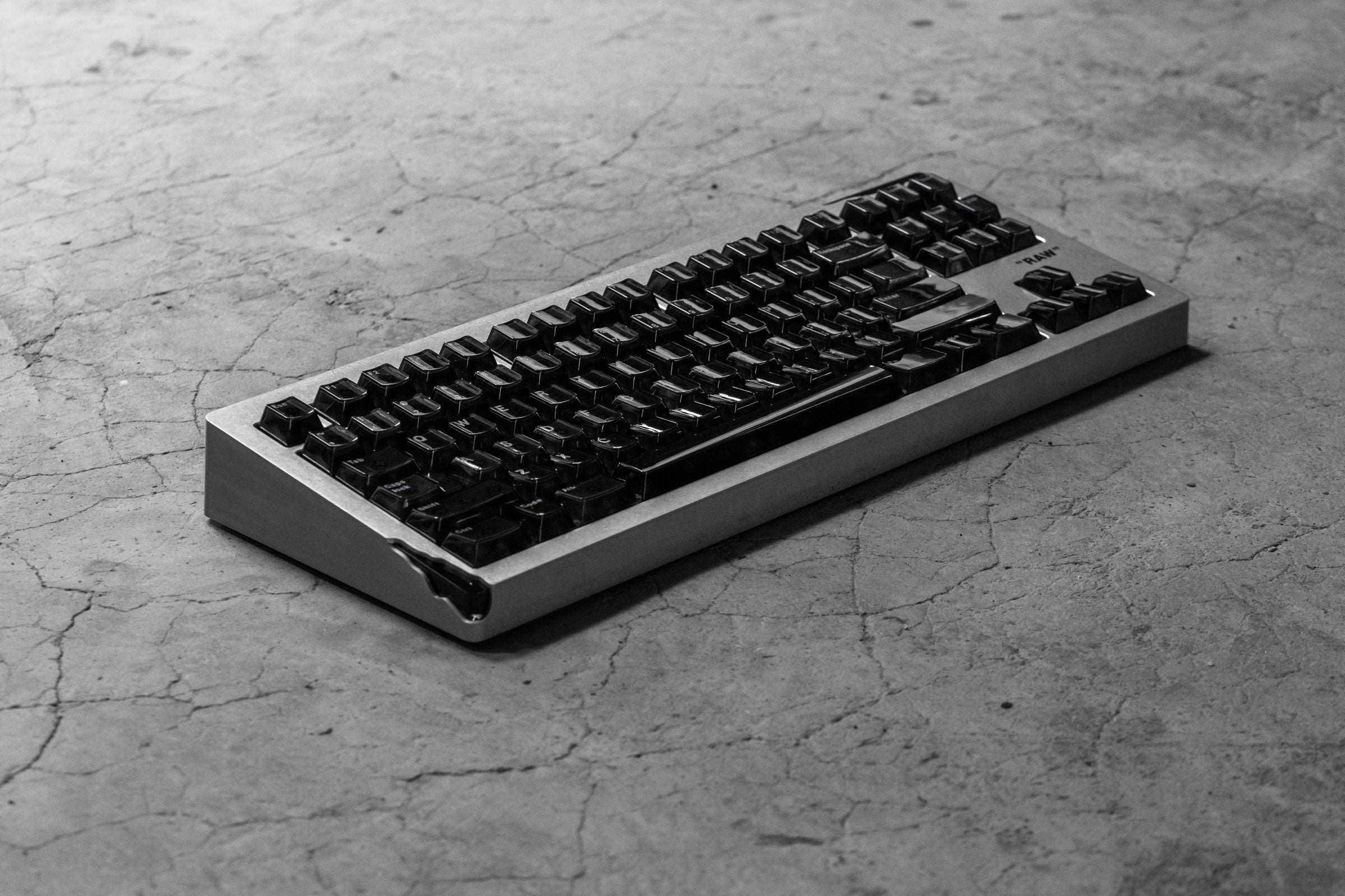 Three-quarter view of the complete AM Relic 80 RAW keyboard on a textured concrete floor.