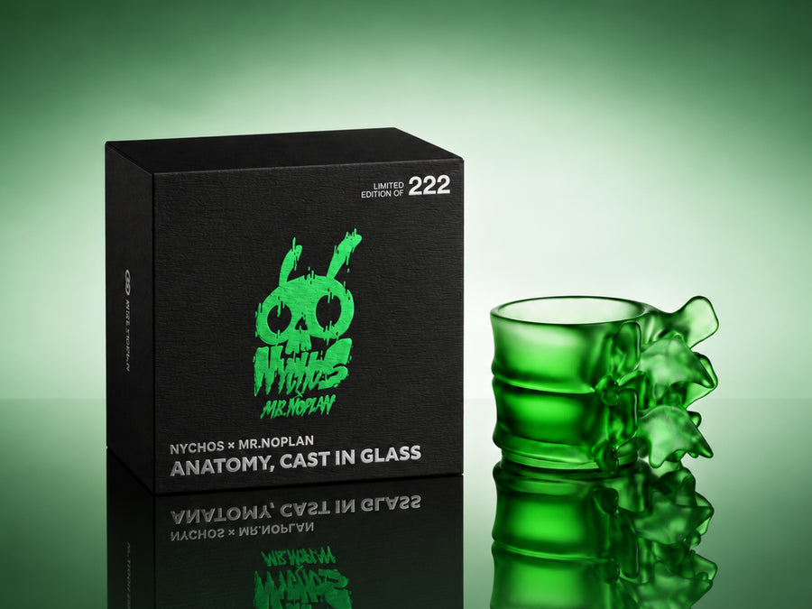 Black NYCHOS × MR.NOPLAN edition box beside the translucent green Spine Whiskey Glass